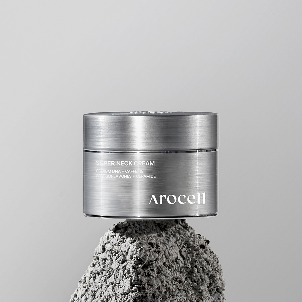 Pot argenté de la Super Neck Cream AROCELL présenté au-dessus d’une pierre grise